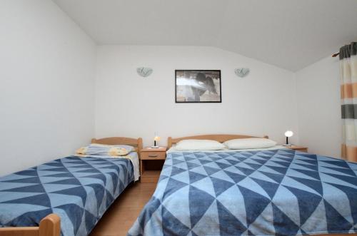a bedroom with two beds and two lights on the wall at Lori Rabac App in Rabac