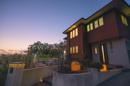 a house with the sunset in the background at 桜島 そらほしのやど幸福365 in Kagoshima