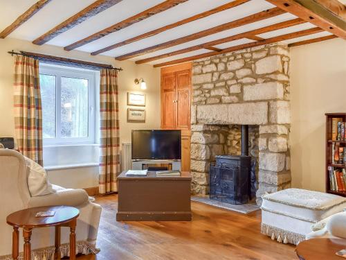 a living room with a stone fireplace and a tv at Pebbles in Castletown