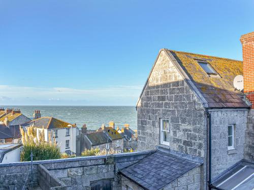 an old stone building with the ocean in the background at Pebbles in Castletown