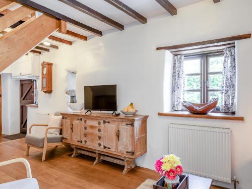a living room with a television and a wooden dresser at The Bing in Buckland in the Moor