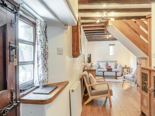 a living room with a staircase and a chair and a table at The Bing in Buckland in the Moor