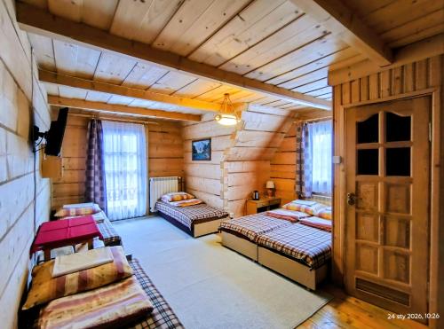 a room with two beds in a log cabin at CHAŁUPA Pokoje Gościnne in Poronin