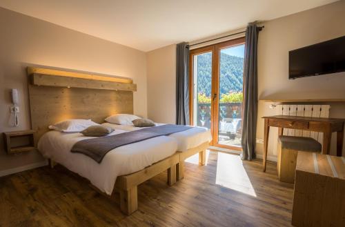 a bedroom with a large bed and a large window at hotel le malgovert SEEZ 73 in Séez