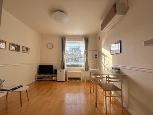 a living room with a table and a television at Blume 中央区温馨小屋 地铁西18丁目站步行10分钟 in Sapporo
