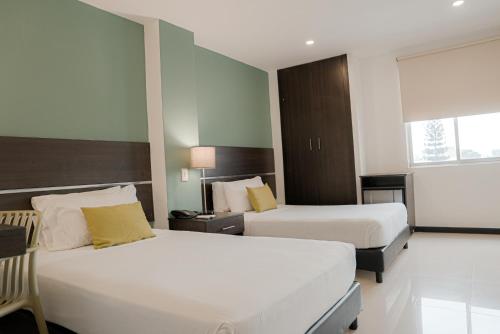 a hotel room with two beds and a window at Basic Hotel Chipichape by Hoteles MS in Cali