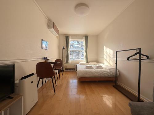 a bedroom with a bed and a table and a television at Blume 中央区温馨小屋 地铁西18丁目站步行10分钟 in Sapporo