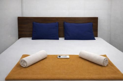 a bed with blue pillows and two rolled towels at Patel's Guest House in Surat