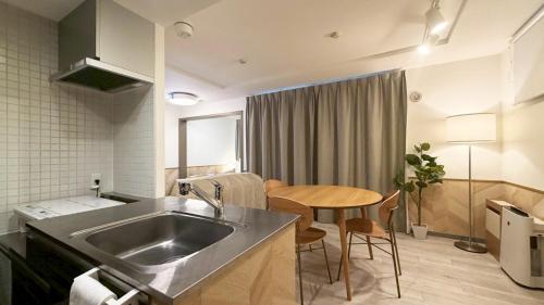 a kitchen with a sink and a table in a room at Glass Shiseikan in Sapporo