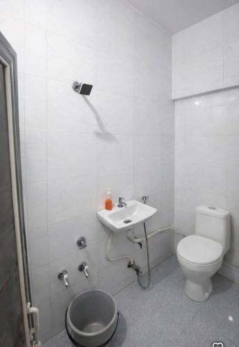 a white bathroom with a toilet and a sink at Patel's Guest House in Surat