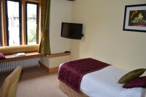 a hotel room with a bed and a television at Canterbury Cathedral Lodge in Canterbury