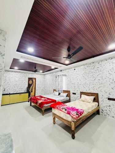 two beds in a room with a ceiling at Tunga sadan in Mādhavaram