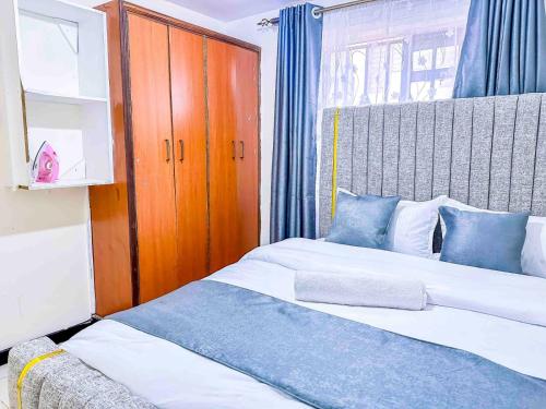 a bedroom with two beds and a wooden cabinet at GILGAL Homes in Kisii