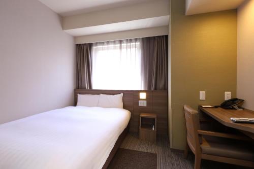 a hotel room with a bed and a desk at Dormy Inn Premium Fukui Natural Hot Spring in Fukui