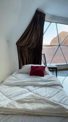 a bed in a bedroom with a large window at Silent Sands in Wadi Rum