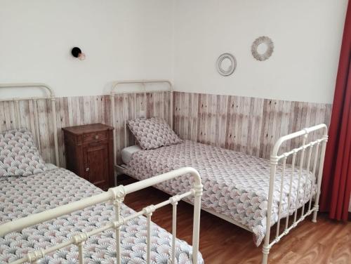 a room with two beds and a wooden wall at Gîte de St Jean in Verdalle