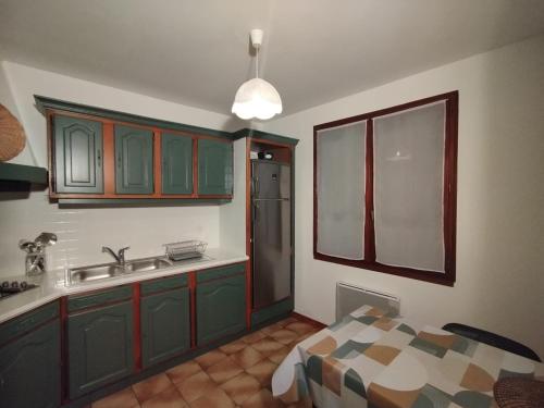 a kitchen with green cabinets and a sink at Gîte de St Jean in Verdalle
