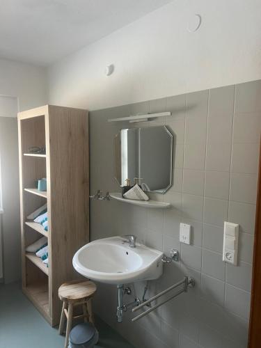 a bathroom with a sink and a mirror and a stool at Ferienwohnung Landliebe in Pinswang