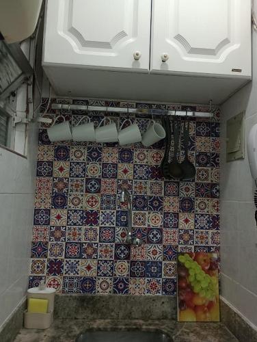 a kitchen with a tiled wall with a sink at Apto Turismo da Serra in Teresópolis