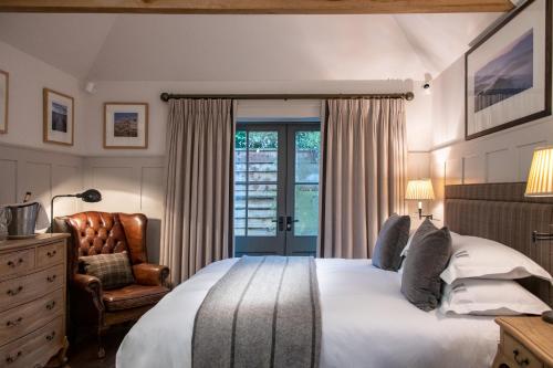 a bedroom with a bed and a chair and a window at Hurley House Hotel in Hurley