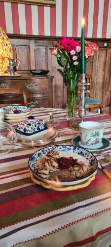 a table topped with plates and a vase with flowers at Le Château de La Coste in Saint-Julien
