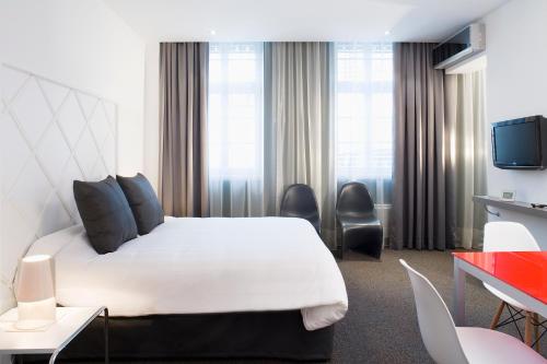 une chambre d'hôtel avec un lit blanc et des chaises dans l'établissement Villa Diana, à Molsheim