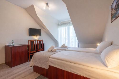 a bedroom with a large bed and a tv at Pensjonat Perła Pienin in Grywałd