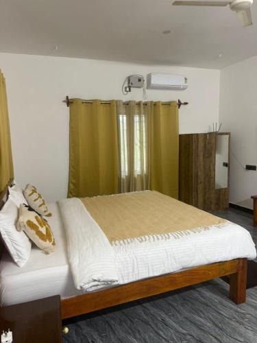 a bedroom with a large bed with green curtains at Patnem Bliss in Canacona