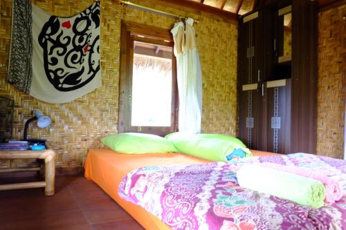 una camera da letto con un letto con cuscini e una finestra di Pondok Indah Bungalows Tetebatu a Tetebatu