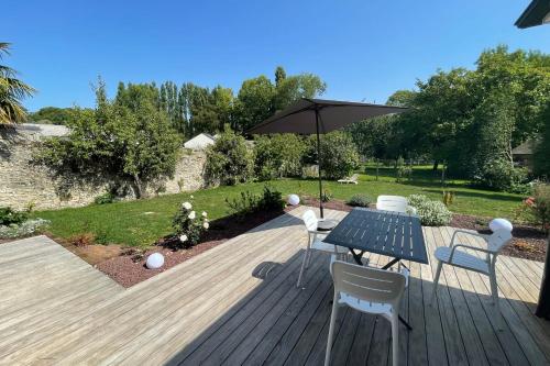 a wooden deck with a table and chairs and an umbrella at Le Clos des Marmuzots parking & garden in Bayeux