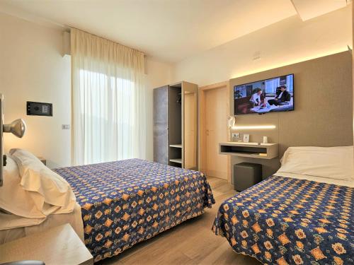 a hotel room with two beds and a flat screen tv at Hotel Ornella in Lido di Jesolo
