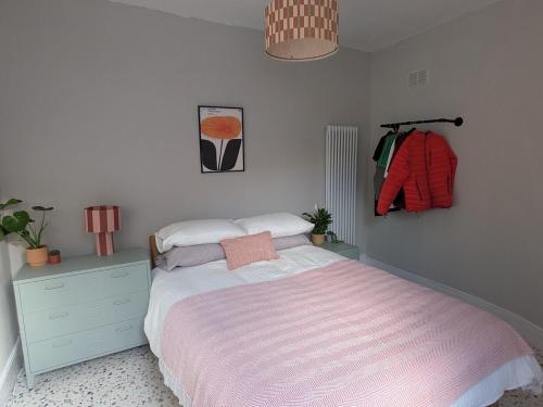 a bedroom with a bed and a dresser with a pink blanket at Tranquil flat in vibrant Nether Edge in Nether Edge