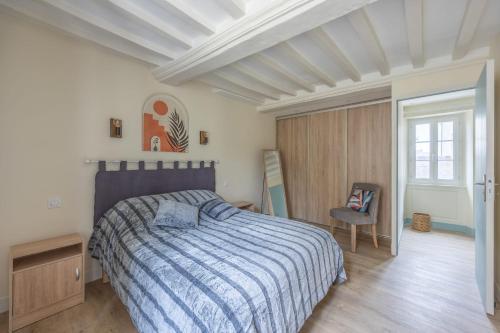 a bedroom with a bed and a chair in it at Les Colibris little house in the city-center in Arromanches-les-Bains