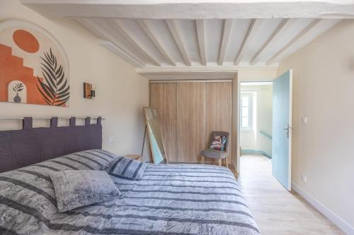 a bedroom with a bed and a chair in it at Les Colibris little house in the city-center in Arromanches-les-Bains