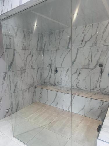 a shower with marble walls and wooden shelves at Banabaka spa and venue in White River