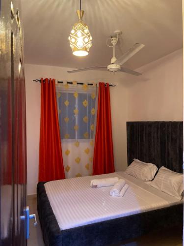 a bedroom with a bed with red curtains at Zuribreezhomes in Bamburi