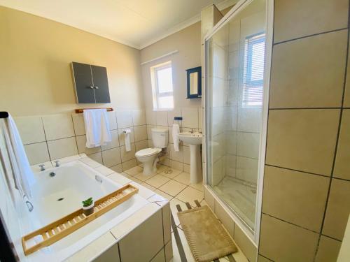 a bathroom with a tub and a toilet and a shower at The Grey Ivory in Port Alfred