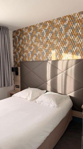 ein Schlafzimmer mit einem großen weißen Bett mit Metallkopfteil in der Unterkunft Hôtel Le Goëlo - Port de Paimpol in Paimpol