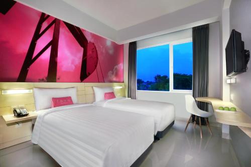 a bedroom with a large white bed and a pink painting at favehotel Sudirman Bojonegoro in Bojonegoro