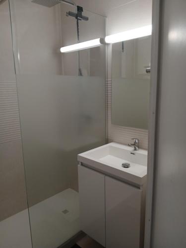 a white bathroom with a sink and a mirror at Studio cabine Thalacap Vue mer in Banyuls-sur-Mer