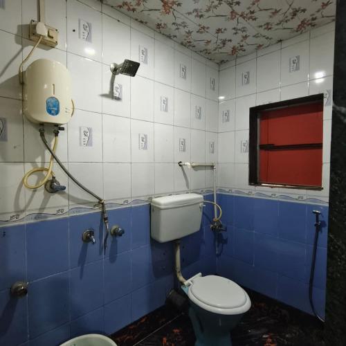 a blue and white bathroom with a toilet and a window at Sai Lodging And Boarding in Dombivli