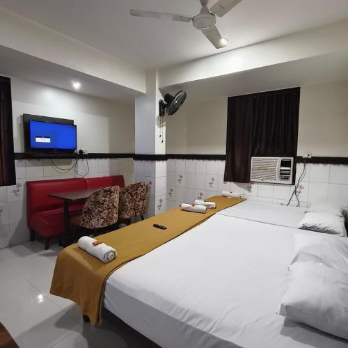 a bedroom with a large white bed and a tv at Sai Lodging And Boarding in Dombivli