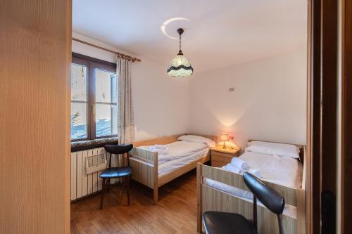 a bedroom with two beds and a desk and a chair at Casa Tre Corone, sulla strada per Cortina in Borca di Cadore