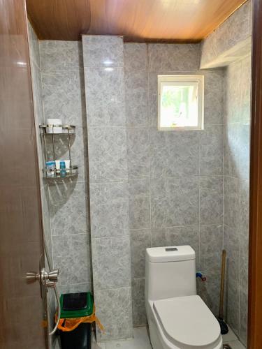 a bathroom with a toilet and a tile wall at Villa with Beachfront Access in Lalauigan