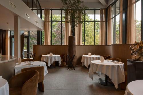 a restaurant with tables and chairs and windows at Hotel Gastronomique de Echoput in Apeldoorn