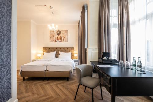 a bedroom with a bed and a desk with a chair at Hotel Alex an der Ahr in Bad Neuenahr-Ahrweiler