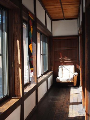 a room with a chair in a room with windows at The Asagiri Guest House in Tanabe