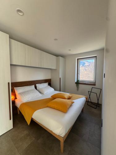 a bedroom with a large bed with orange and white pillows at Graziosa, Casetta in Valgerola in Rasura