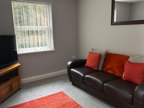 a living room with a black leather couch and a television at New Road Apartment - 2 Bedrooms - Sleeps 3 in Whitehaven