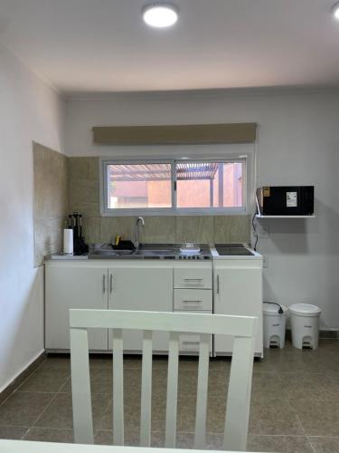 a white kitchen with a sink and a window at Fully equipped studio apartments in Apóstoles